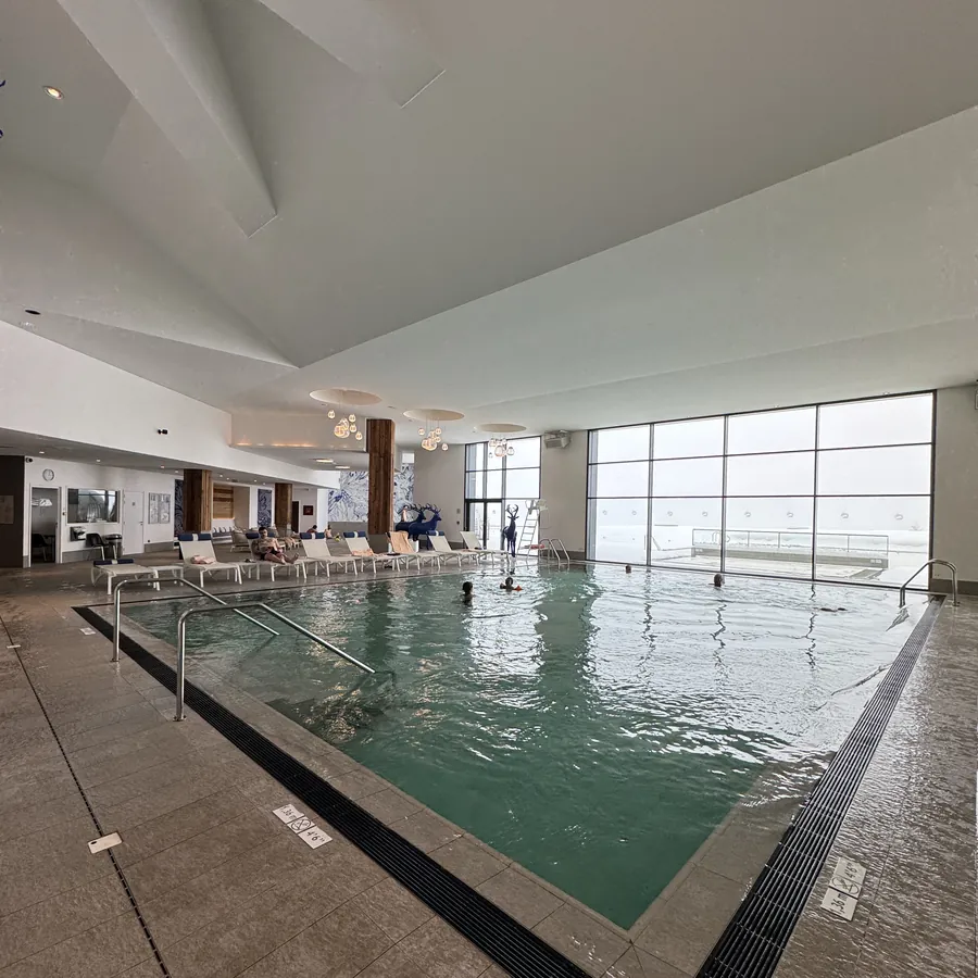 Piscina interna do resort com espreguiçadeiras e vista para a montanha