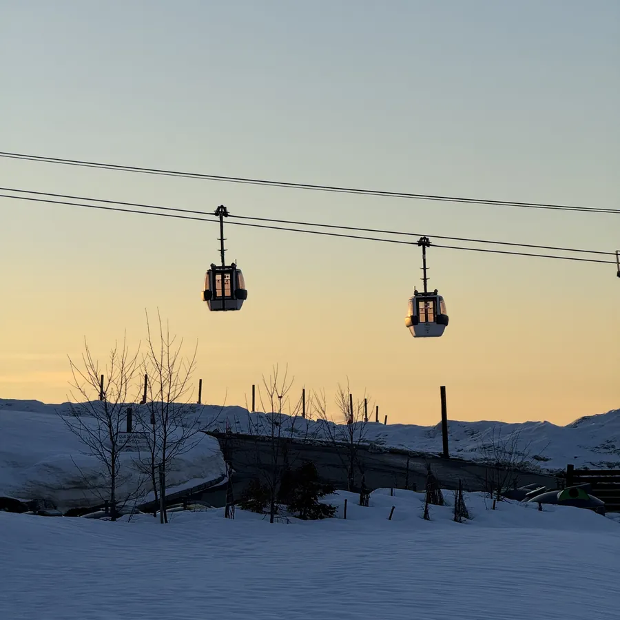 Cabines do teleférico da estação contra o céu alaranjado do fim da tarde